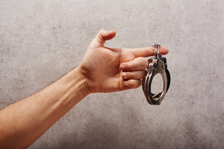 Person holds handcuffs with index finger